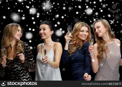 new year party, christmas, winter holidays and people concept - happy women with champagne glasses and dancing over black background with snow