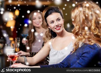 new year party, christmas, winter holidays and people concept - happy women drinking champagne and cocktails at night club over snow