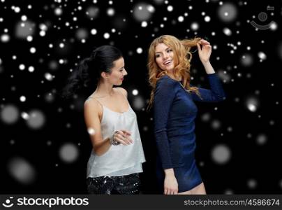new year party, christmas, winter holidays and people concept - happy young women dancing at night club disco over black background with snow