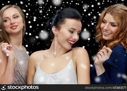 new year party, christmas, winter holidays and people concept - happy young women dancing over black background with snow