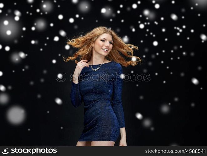 new year party, christmas, winter holidays and people concept - happy young redhead woman dancing at night club disco over black background with snow