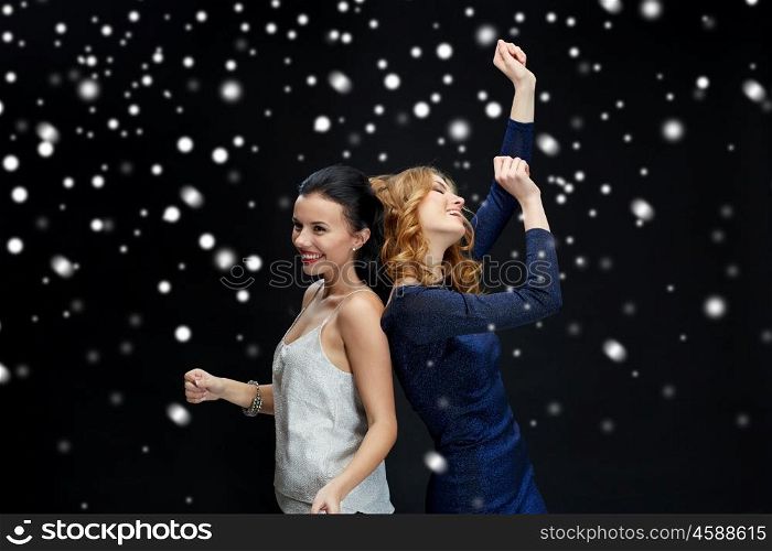 new year party, christmas, winter holidays and people concept - happy young women dancing at night club disco over black background with snow