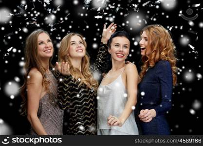 new year party, christmas, winter holidays and people concept - happy young women dancing over black background with snow