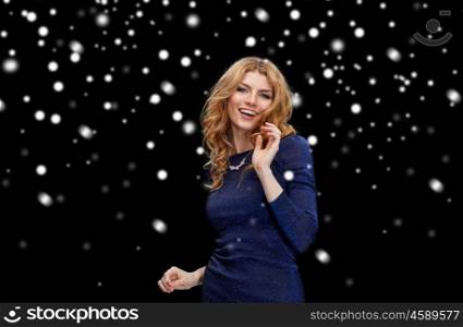 new year party, christmas, winter holidays and people concept - happy young redhead woman dancing at night club disco over black background with snow