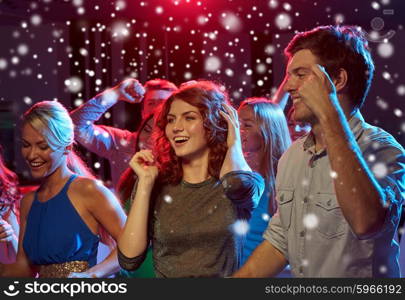 new year party, holidays, celebration, nightlife and people concept - group of happy friends dancing in night club and snow effect