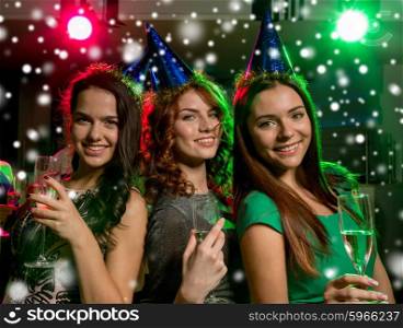 new year party, holidays, celebration, nightlife and people concept - smiling friends with glasses of non-alcoholic champagne in club and snow effect