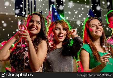 new year party, holidays, celebration, nightlife and people concept - smiling friends with glasses of non-alcoholic champagne in club and snow effect