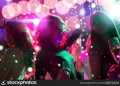 new year party, holidays, celebration, nightlife and people concept - smiling friends with glasses of non-alcoholic champagne dancing at night club and snow effect