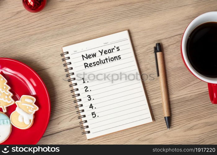 New Year Resolution with notebook, black coffee cup, Christmas cookies and pen on wood table. Xmas, Happy New Year, Goals, To do list, Strategy and Plan concept