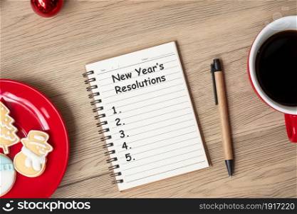 New Year Resolution with notebook, black coffee cup, Christmas cookies and pen on wood table. Xmas, Happy New Year, Goals, To do list, Strategy and Plan concept