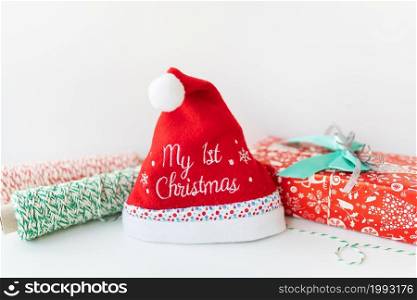 New Year&rsquo;s hat for a baby with the inscription my first Christmas on a background of gifts. New Year&rsquo;s hat for a baby with the inscription my first Christmas on a background of gifts.