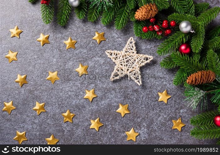 New Year template with Christmas decoration holidays. Top view flat lay of border green fir tree branches with Xmas ornaments and the star on concrete table background with copy space for text
