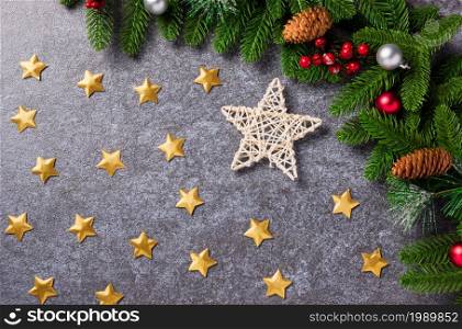 New Year template with Christmas decoration holidays. Top view flat lay of border green fir tree branches with Xmas ornaments and the star on concrete table background with copy space for text