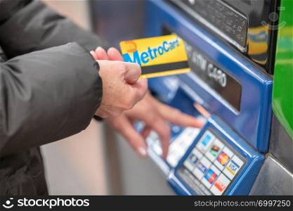NEW YORK CITY - DECEMBER 1, 2018: Woman charges her metrocard at a fill station. Metrocard allows you to travel on NYC public transport.