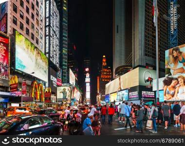 NEW YORK CITY - SEPTEMBER 05: Times square with people in the night on October 5, 2015 in New York City. It's major commercial intersection and neighborhood in Midtown Manhattan at the junction of Broadway and 7th Avenue.