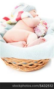 Newborn baby boy in the crochet hat lay in basket, focus on the feet
