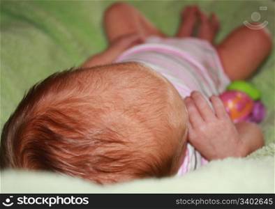 Newborn baby girl laying on a soft green blanket