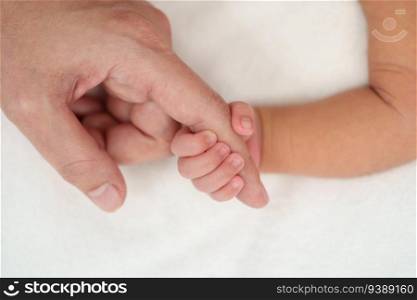newborn baby hand holding index finger of mother on a bed