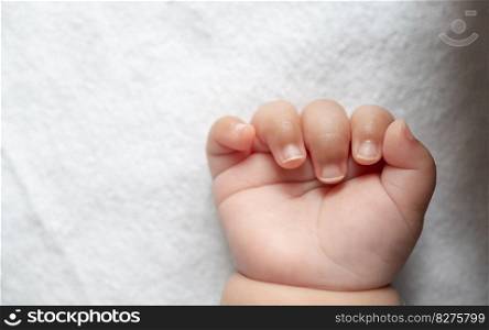 Newborn baby hand in white bed. Selective focus.