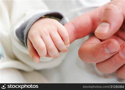 Newborn baby holding father&acute;s finger