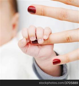 Newborn baby holding mother&acute;s finger