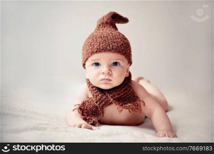 newborn baby in cap and scarf looking into the camera. newborn baby in a cap and scarf
