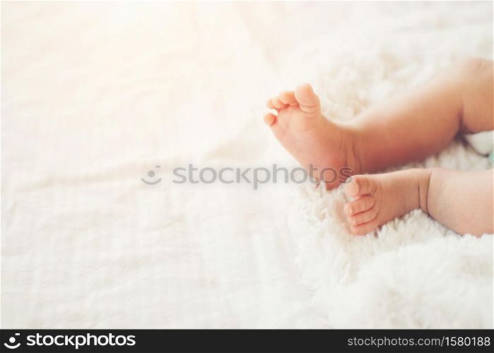 Newborn Baby legs on white bed.