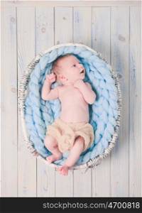 Newborn baby on blue giant crochet blanket look up. The newborn baby