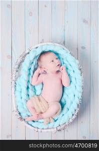 Newborn baby on blue giant crochet blanket look up. The newborn baby