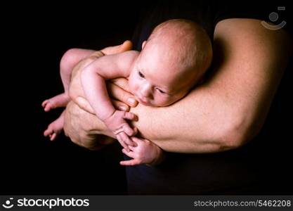 Newborn baby on the father&#39;s hands on black
