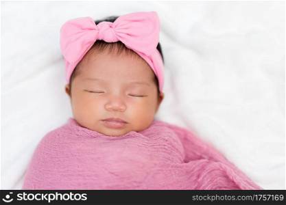 newborn baby sleep in pink cloth wrap blanket on a bed