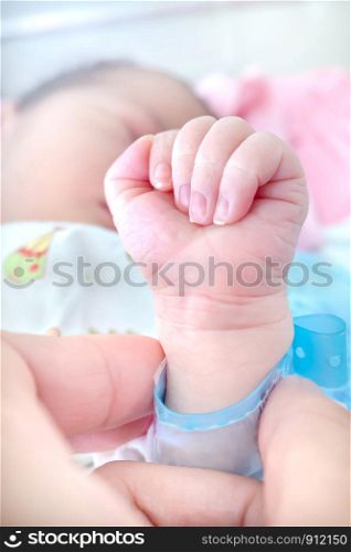 Newborn baby touching hands. Closeup of family hands holding each other with love.