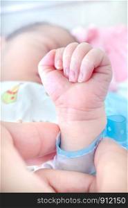 Newborn baby touching hands. Closeup of family hands holding each other with love.