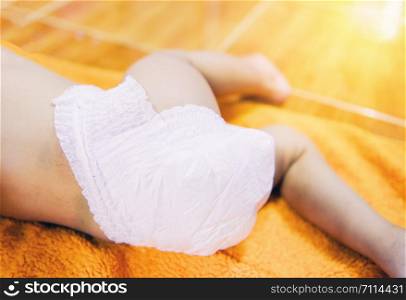 Newborn baby with Diapers / child wear white diaper and playing on a orange knitted blanket in the nursery