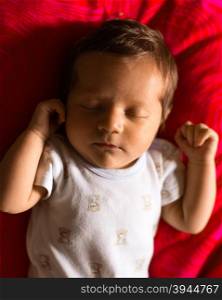 Newborn boy sleeping peacefully on a red background