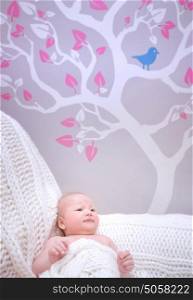 Newborn girl in cute baby room, gentle stylish interior of bedroom, beautiful picture on wallpaper, happy childhood concept