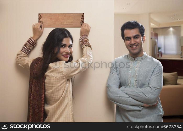 Newlywed couple in traditional dress placing name plate to home