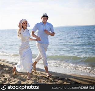 Newlywed couple running on beach