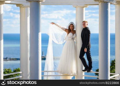 Newlyweds in a beautiful gazebo stand on a metal railing