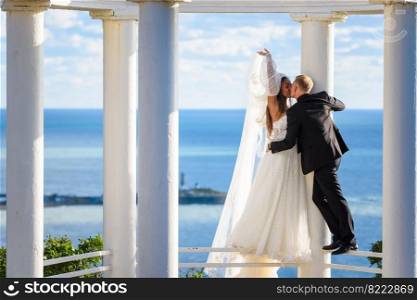Newlyweds kiss in a beautiful gazebo standing on a metal railing
