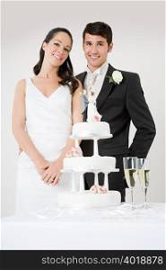 Newlyweds standing by wedding cake
