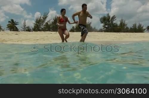 Newlyweds: young adults running and having fun on a tropical beach on the Caribbean sea in Cuba