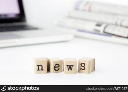 news concept with laptop and newspaper, close-up wooden text