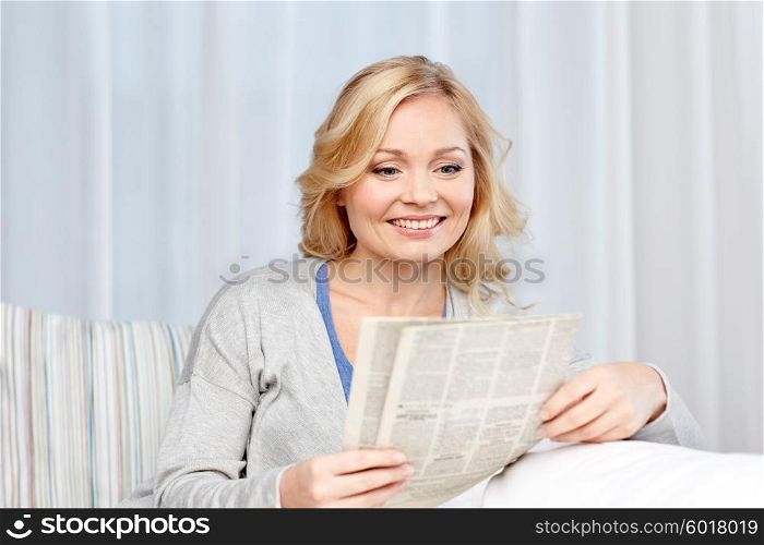 news, press, media, leisure and people concept - smiling woman reading newspaper at home