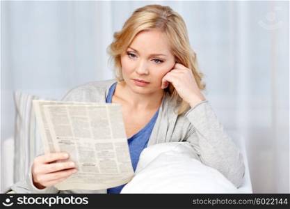news, press, media, leisure and people concept - woman reading newspaper at home