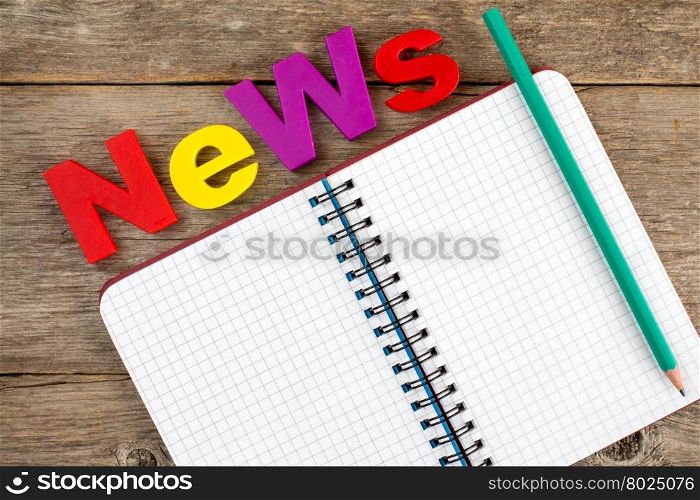 NEWS Text and spiral notebook with pencil on the wooden background