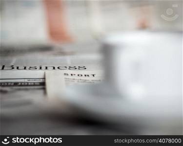 Newspapers and coffee cup macro shot with shallow depth of field