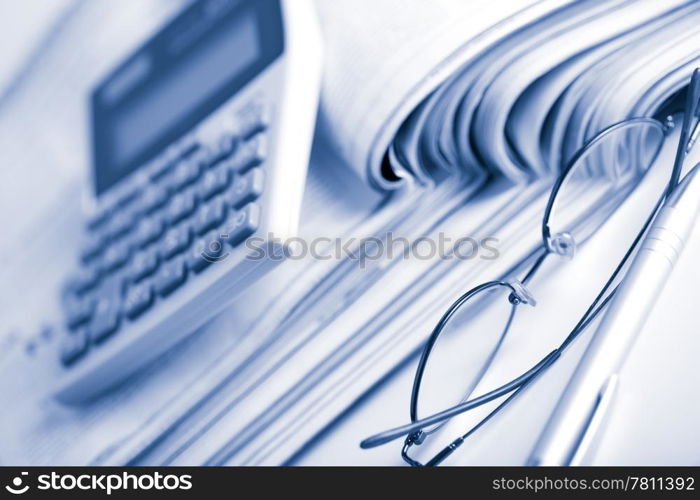 newspapers, calculator and glasses toned blue