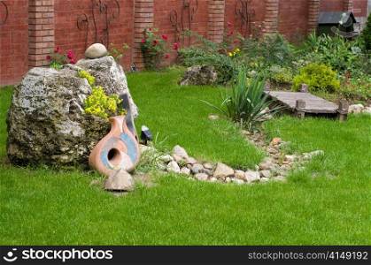 nice backyard decoration, stone with yellow flowers, ceramics on the grass etc. nice backyard decoration