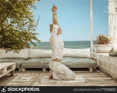 Nice Calm Female Doing Yoga Exercises on the Terrace of Beach House. Meditating on the Beach. Zen Balance. Peaceful Summer Vacation.. Yoga on the Beach